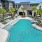 Three-Bedroom Apartments in Land O' Lakes, FL - Everwell at Bexley - Swimming Pool with Cabanas, Tanning Chairs, Umbrellas, Surrounded by Palm Trees