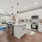 Pet-Friendly Apartments in Land O' Lakes, FL - Everwell at Bexley - Spacious Kitchen with Quartz Countertops, White Subway Tile Backsplash, A Farmhouse Kitchen Island, and Frigidaire Stainless Steel Appliances with Access to Living Room